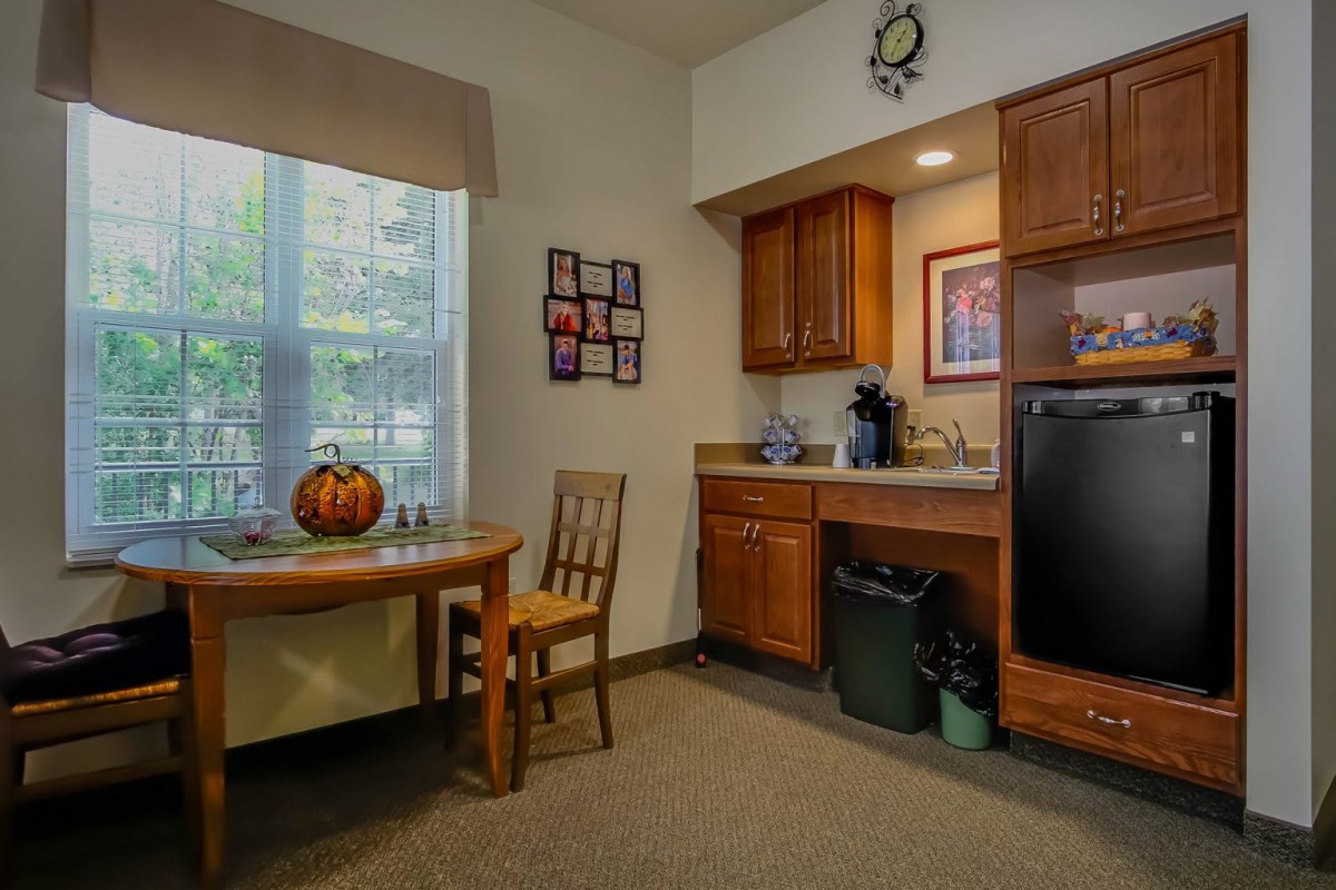 A cozy kitchen nook with a table, chair, and pumpkin decoration next to a compact kitchenette.