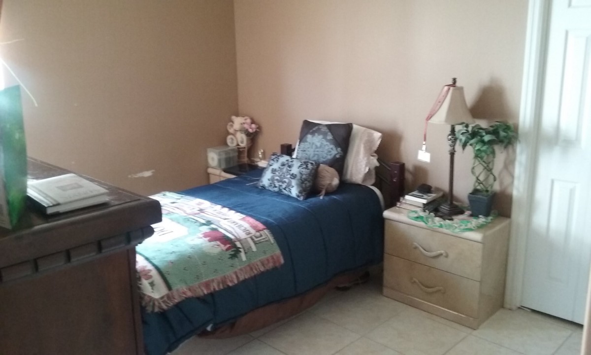 A cozy bedroom with a single bed, decorative pillows, and a nightstand.