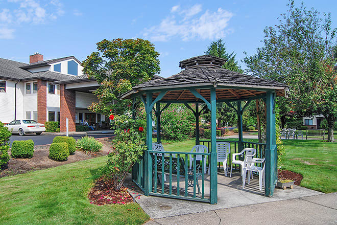 A scenic view of a gazebo surrounded by lush greenery in a garden setting.