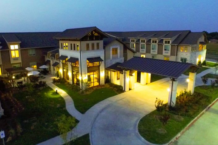 A beautifully lit modern building at dusk with winding pathways.