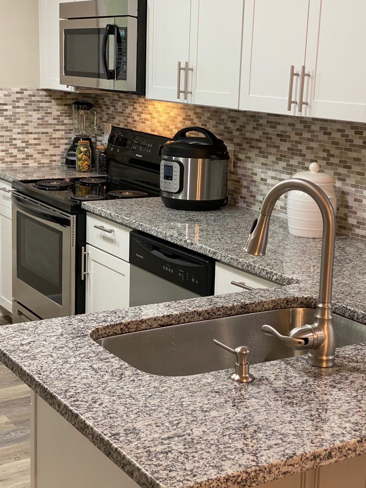 A modern kitchen with granite countertops and various appliances.