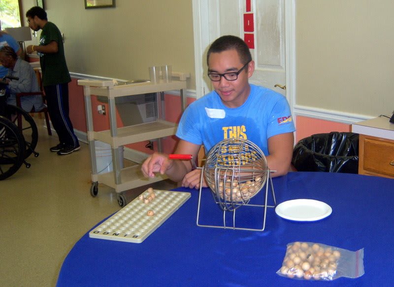A person playing bingo, seated at a table with a bingo cage and numbers.