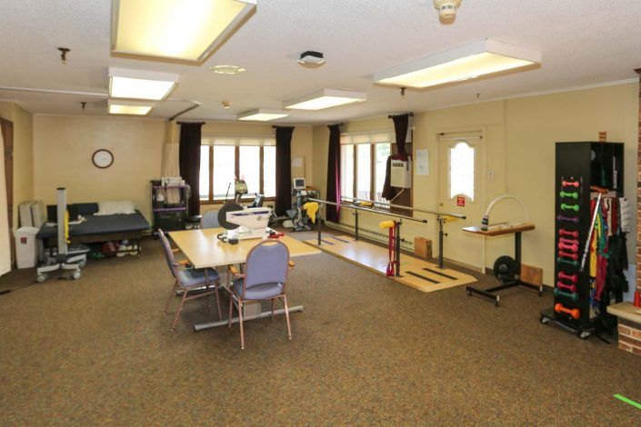 A rehabilitation room equipped with exercise equipment and parallel bars for therapy.