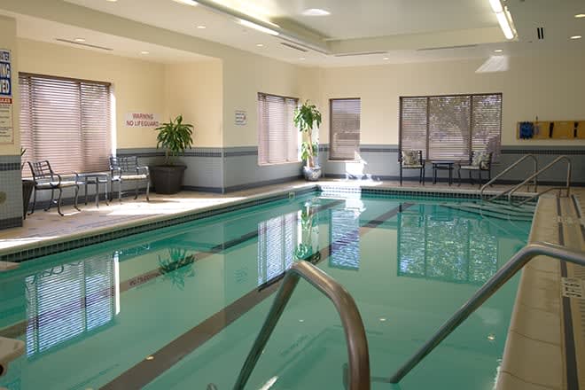 An inviting indoor swimming pool area in a hotel with natural light and seating.