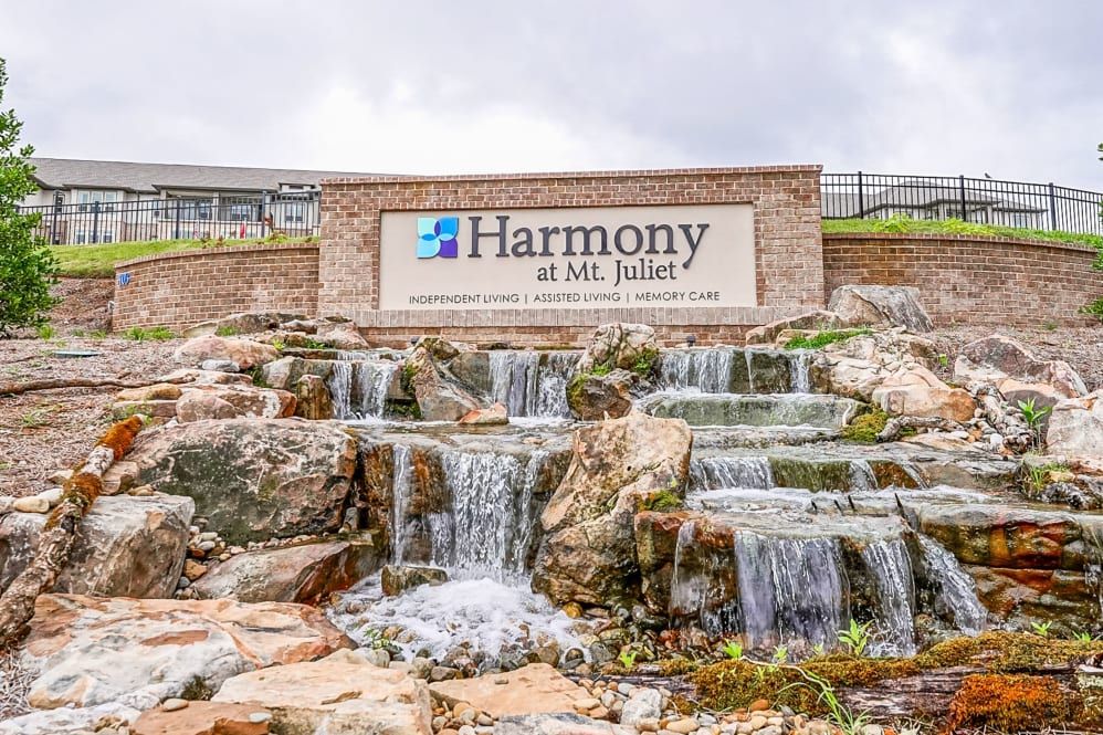 The image shows a landscaped waterfall with a sign for 'Harmony at Mt. Juliet' at the entrance.