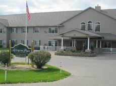 A two-story residential building with a driveway and an American flag in front.