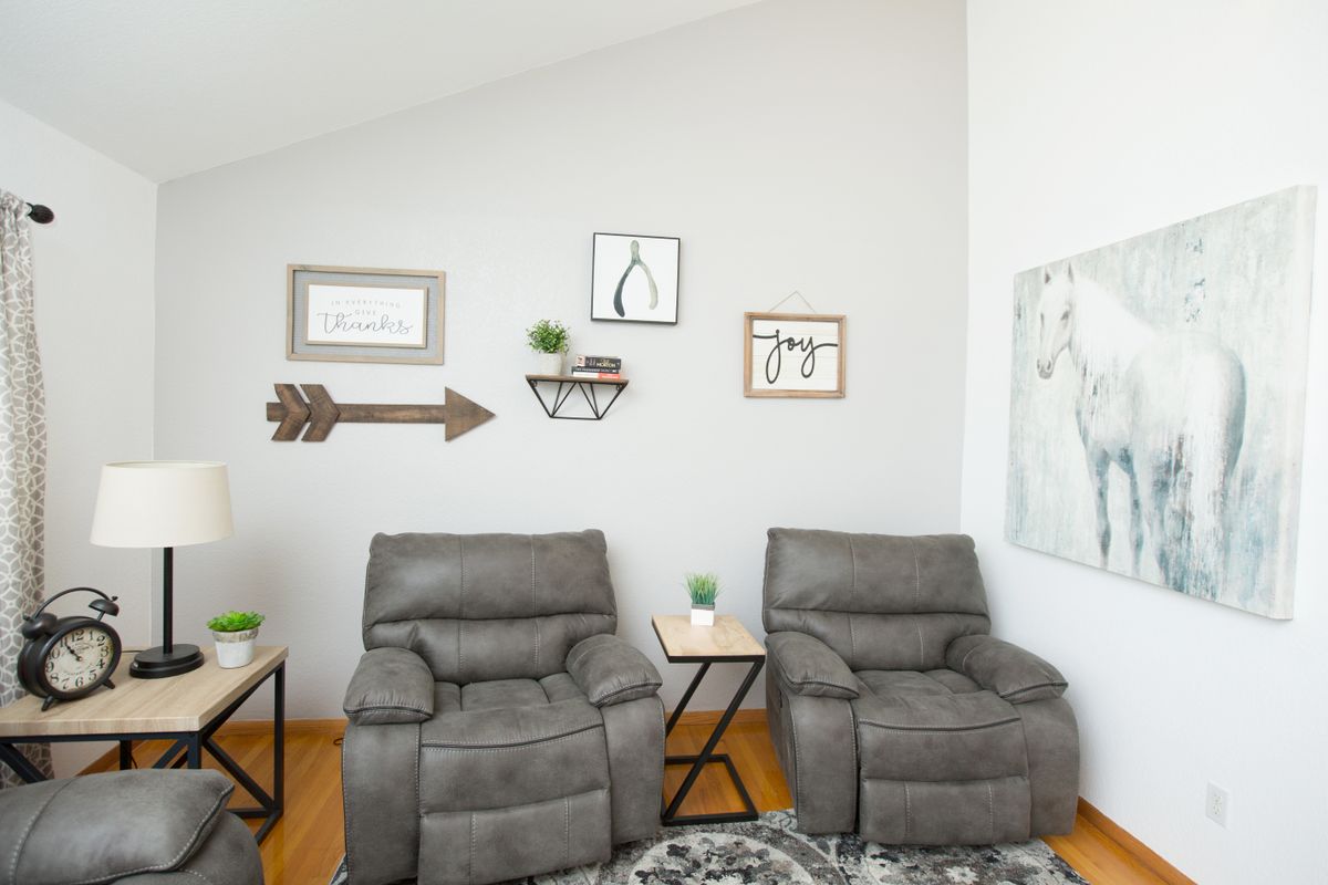 A cozy living room featuring two recliner chairs, stylish wall art, and small indoor plants on side tables.