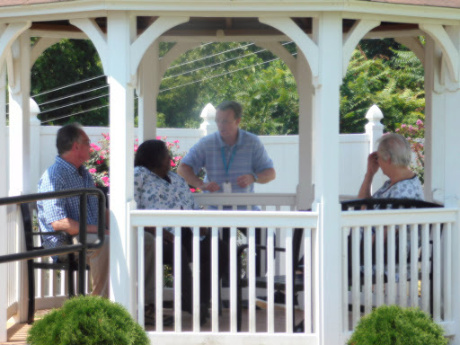 A group of people engaged in conversation under a gazebo on a sunny day.
