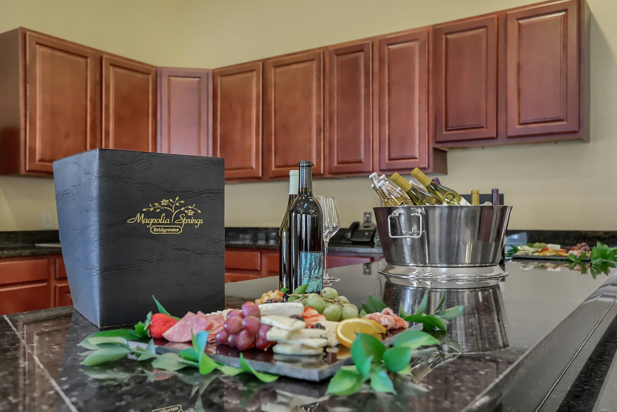 A kitchen countertop featuring a charcuterie board with grapes, cheese, and a bottle of wine.