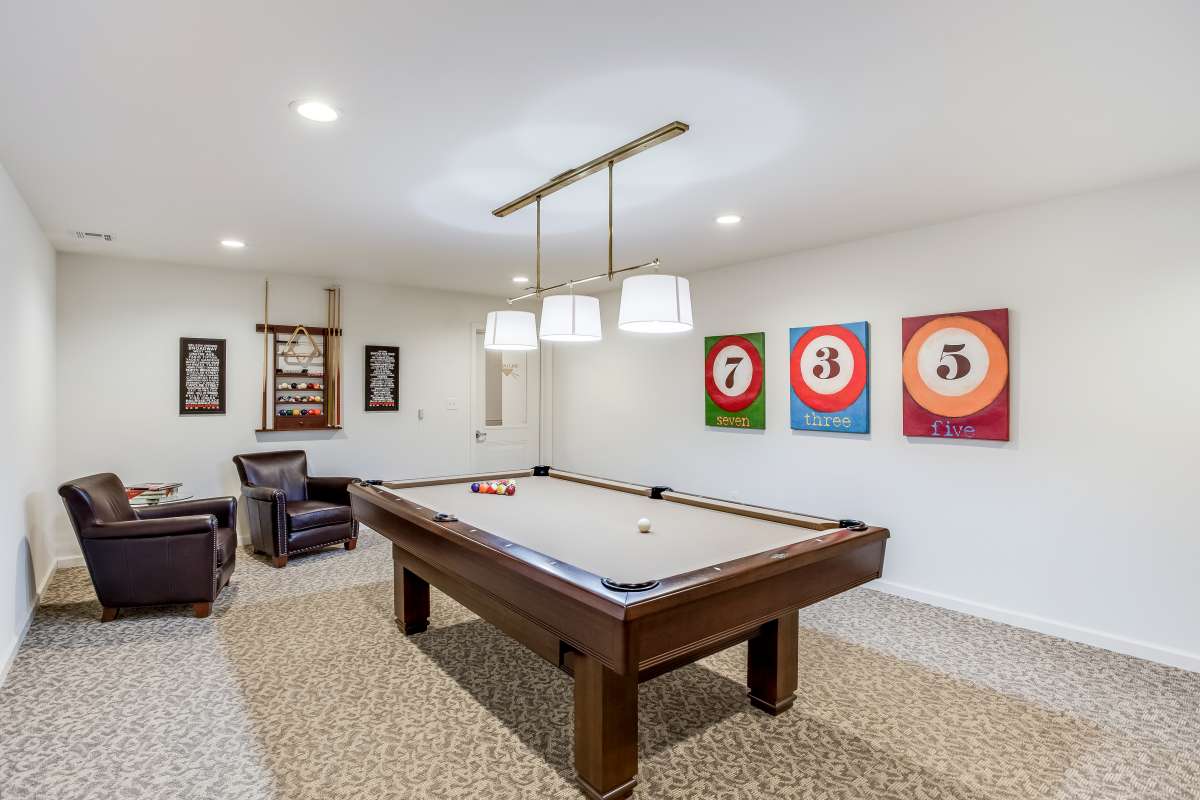 A stylish game room featuring a pool table, modern lighting, and colorful artwork on the walls.