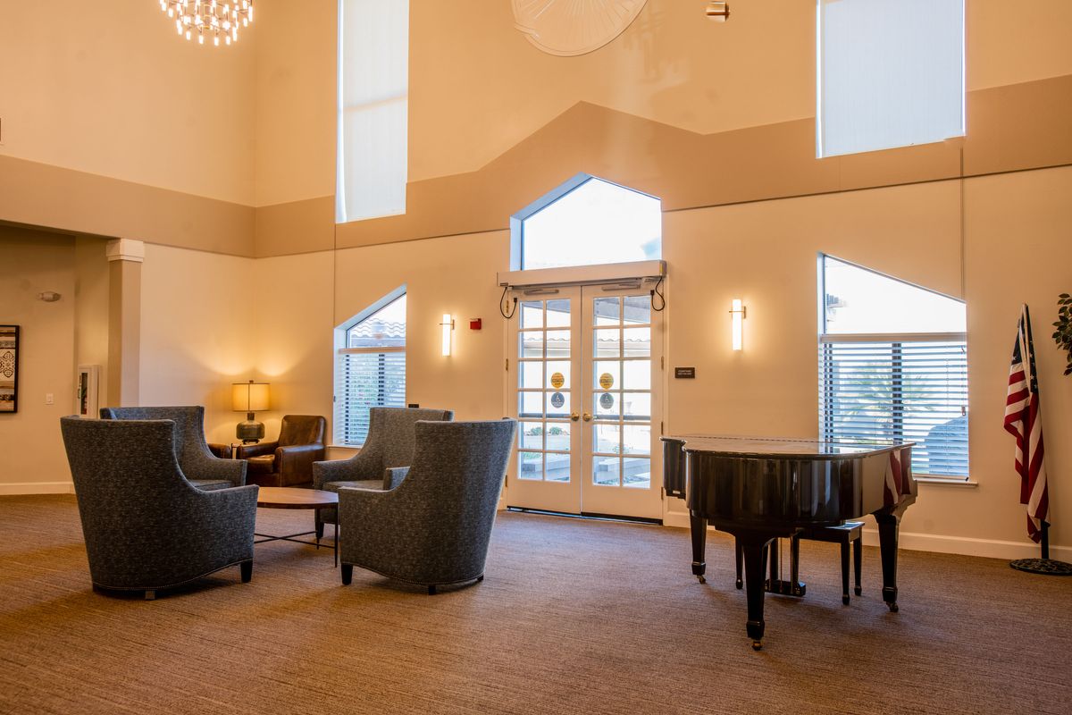 A spacious and elegant lobby featuring a grand piano, comfortable seating, and modern lighting.