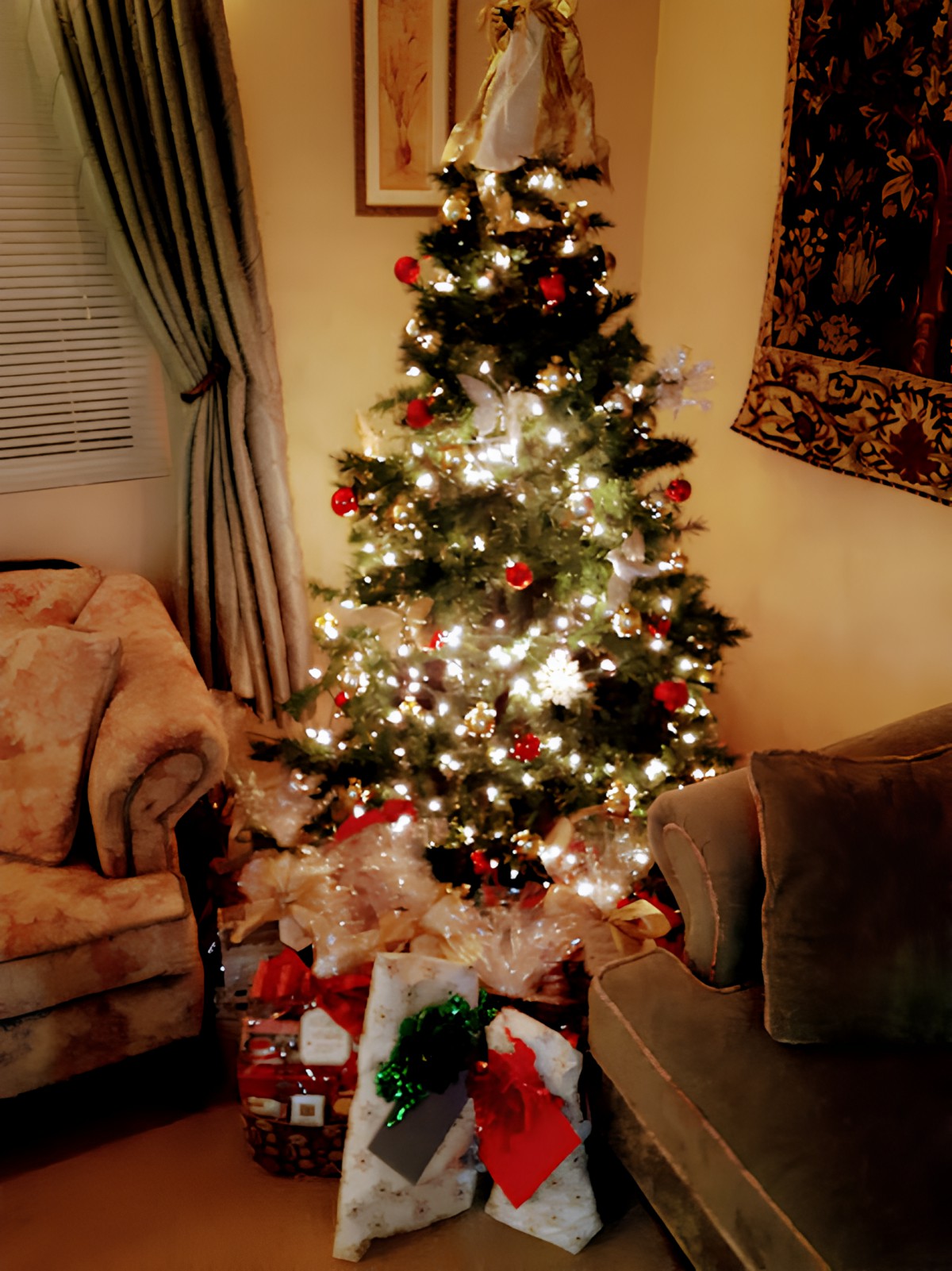 A beautifully decorated Christmas tree with lights and presents in a cozy living room setting.