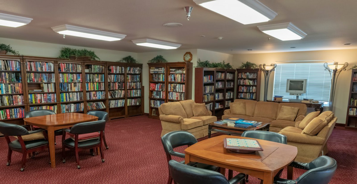 A cozy library room with bookshelves, comfortable seating, and tables for reading.