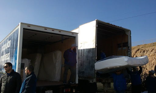 A moving truck is being loaded with items under a clear blue sky.