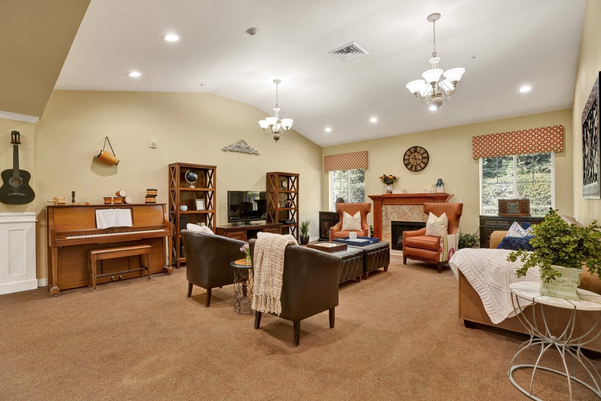 A cozy living room with a piano, comfortable seating, and a fireplace.