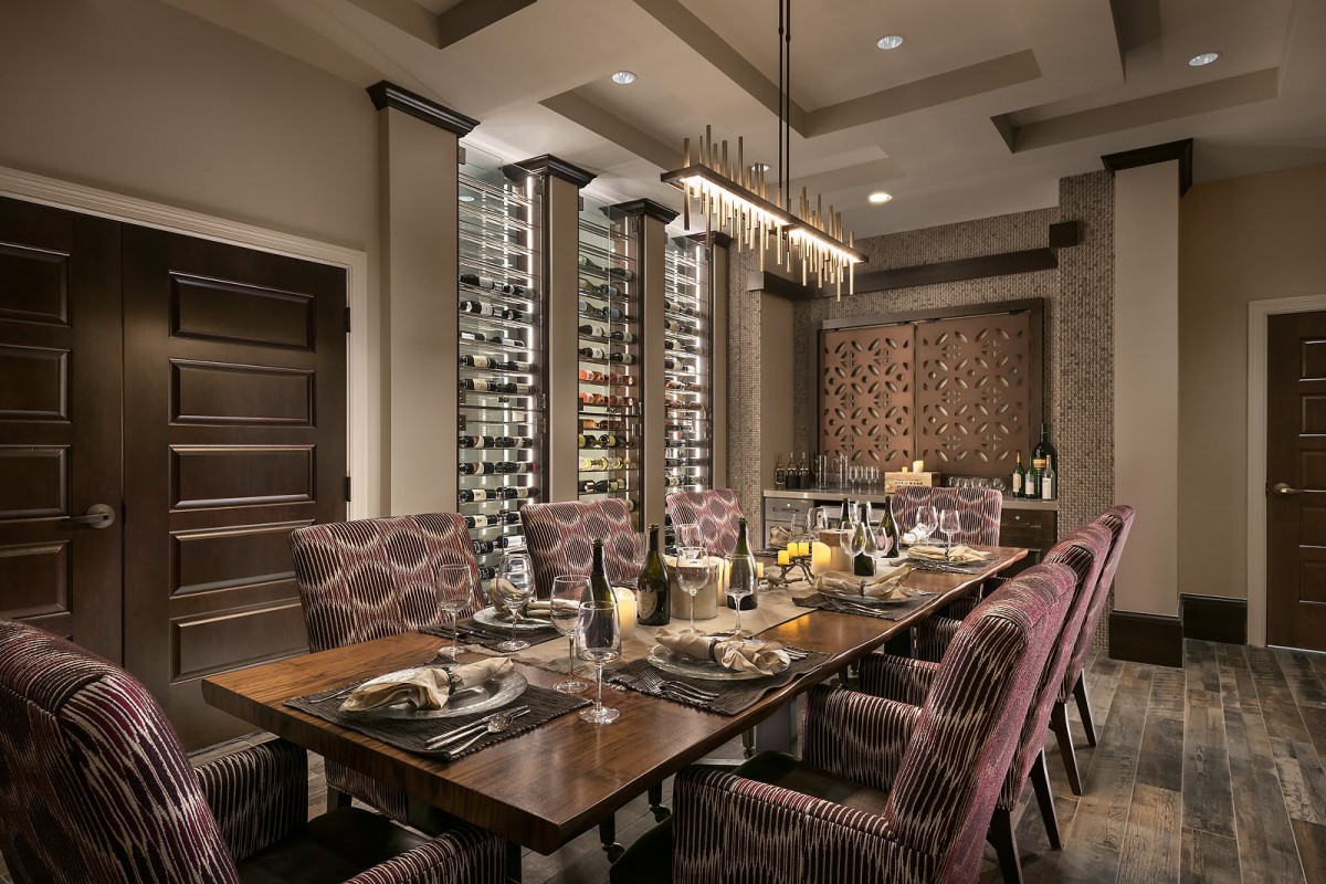 A luxurious dining room with a large wooden table, elegant chairs, and an impressive wine storage feature.
