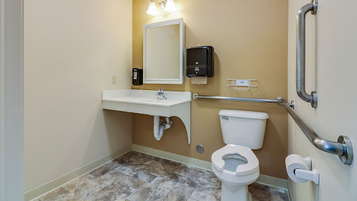 A clean and accessible bathroom featuring a toilet, sink, and hand dryer.