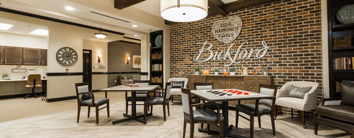 A modern and cozy seating area with tables and chairs, featuring a brick wall and warm lighting.