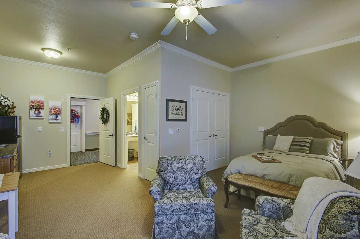 Cozy bedroom with armchair and ceiling fan.