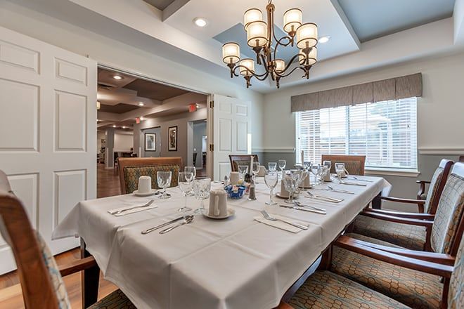 A well-appointed dining room featuring an elegant chandelier, a large table with a white tablecloth and complete place settings.