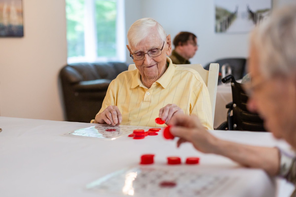 An elderly man playing a game of bingo indoors.
