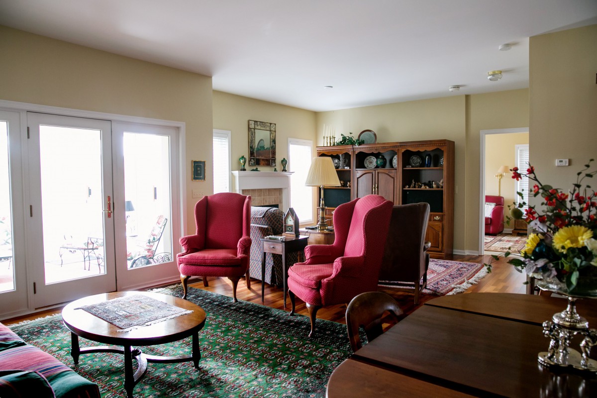 A cozy living room featuring two red armchairs, a wooden coffee table, and a large bookshelf.