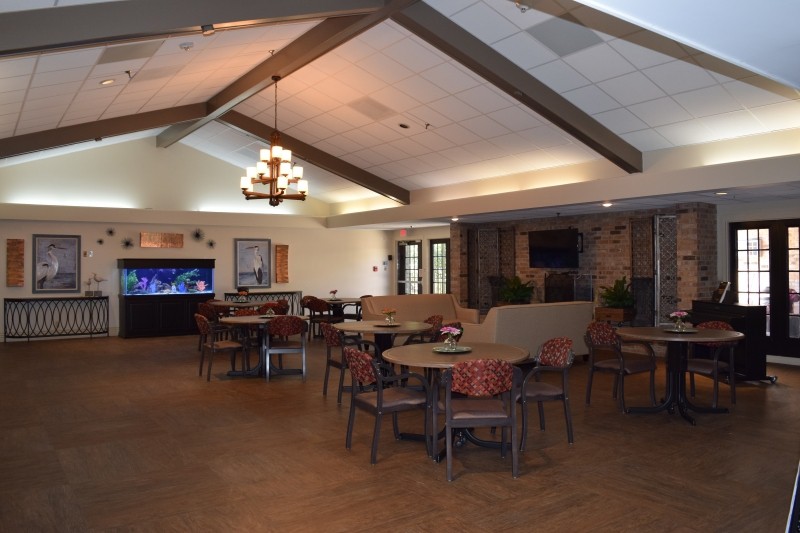 A spacious dining area featuring multiple tables, chairs, a chandelier, and an aquarium.