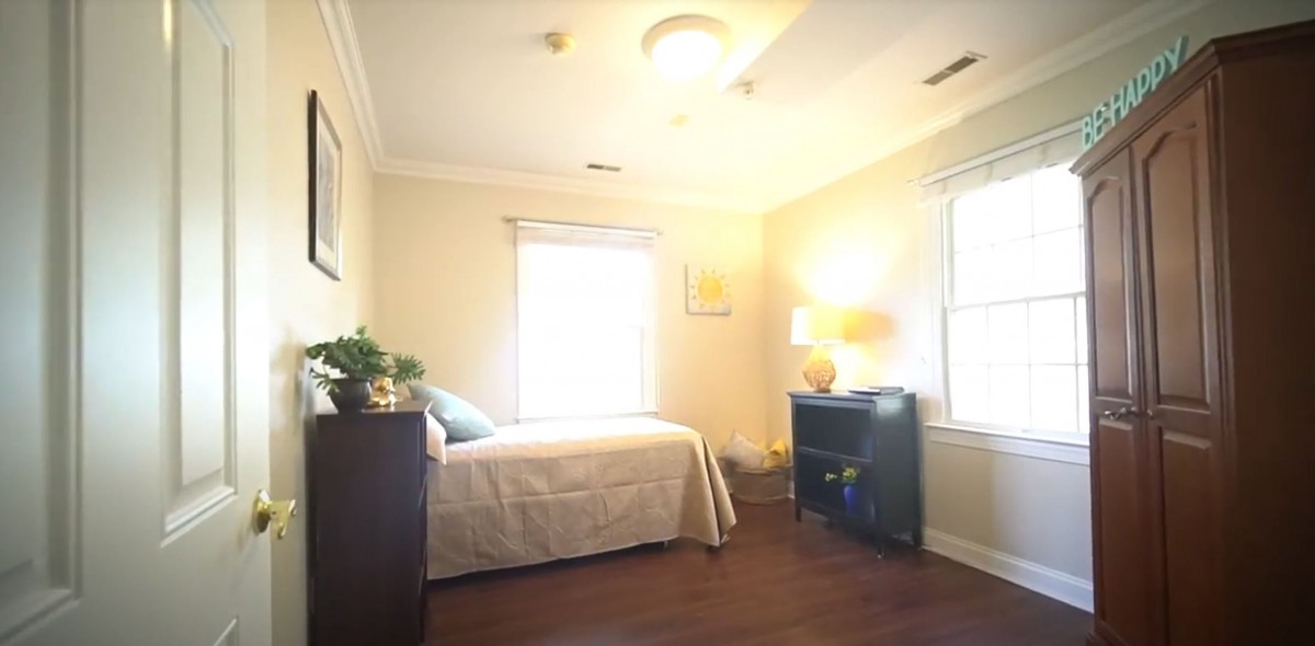 A cozy bedroom with a single bed, lamp, and wooden flooring.