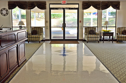 A welcoming lobby area featuring comfortable seating and a polished floor, bathed in natural light from large windows.