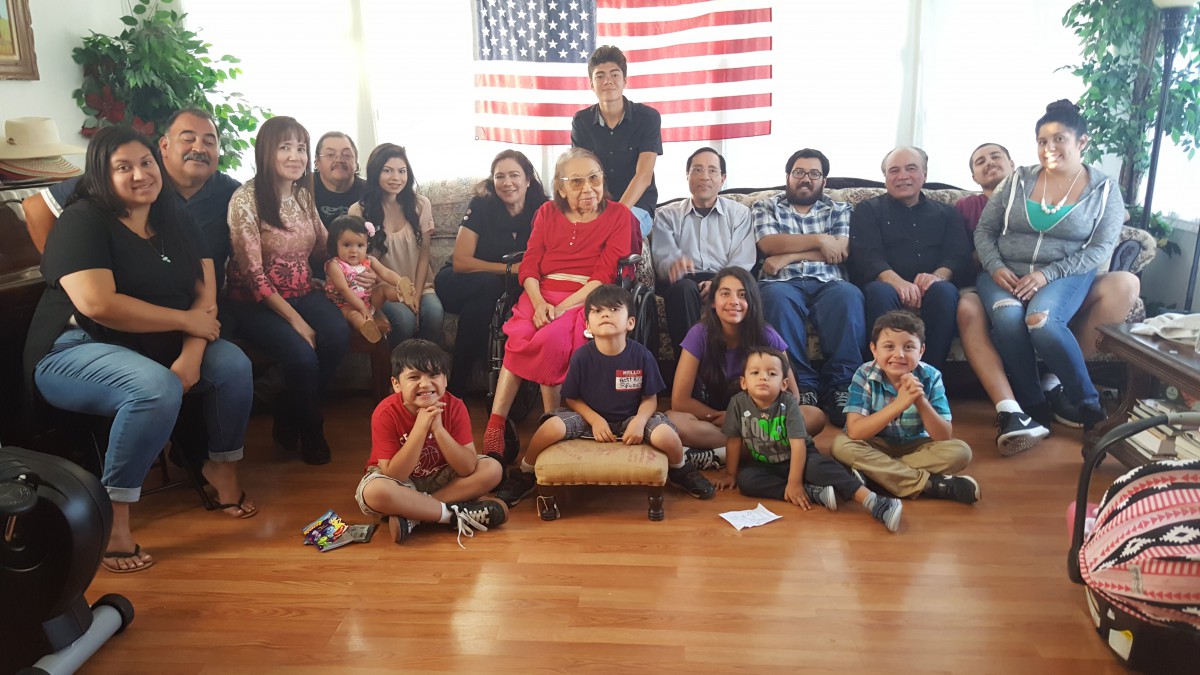 A large family gathers for a group photo in front of an American flag.