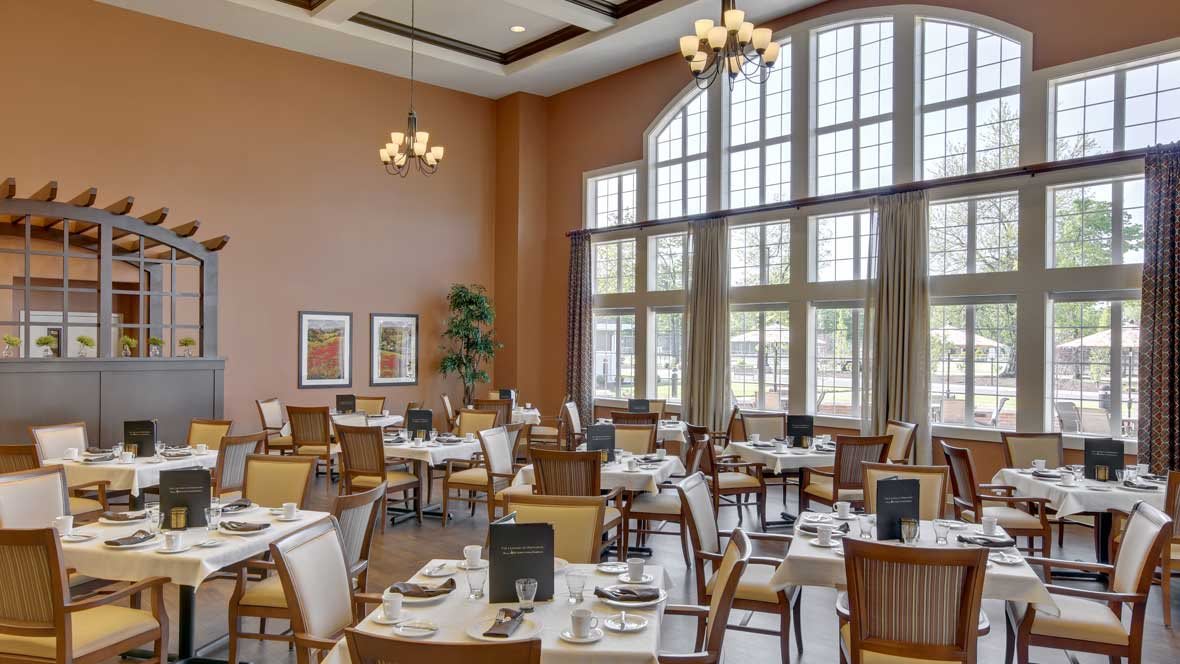 A spacious and elegantly designed restaurant dining area with large windows and neatly arranged tables.