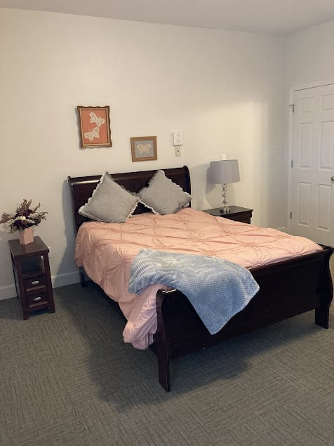 A cozy bedroom with a neatly made bed, featuring two nightstands and lamps.