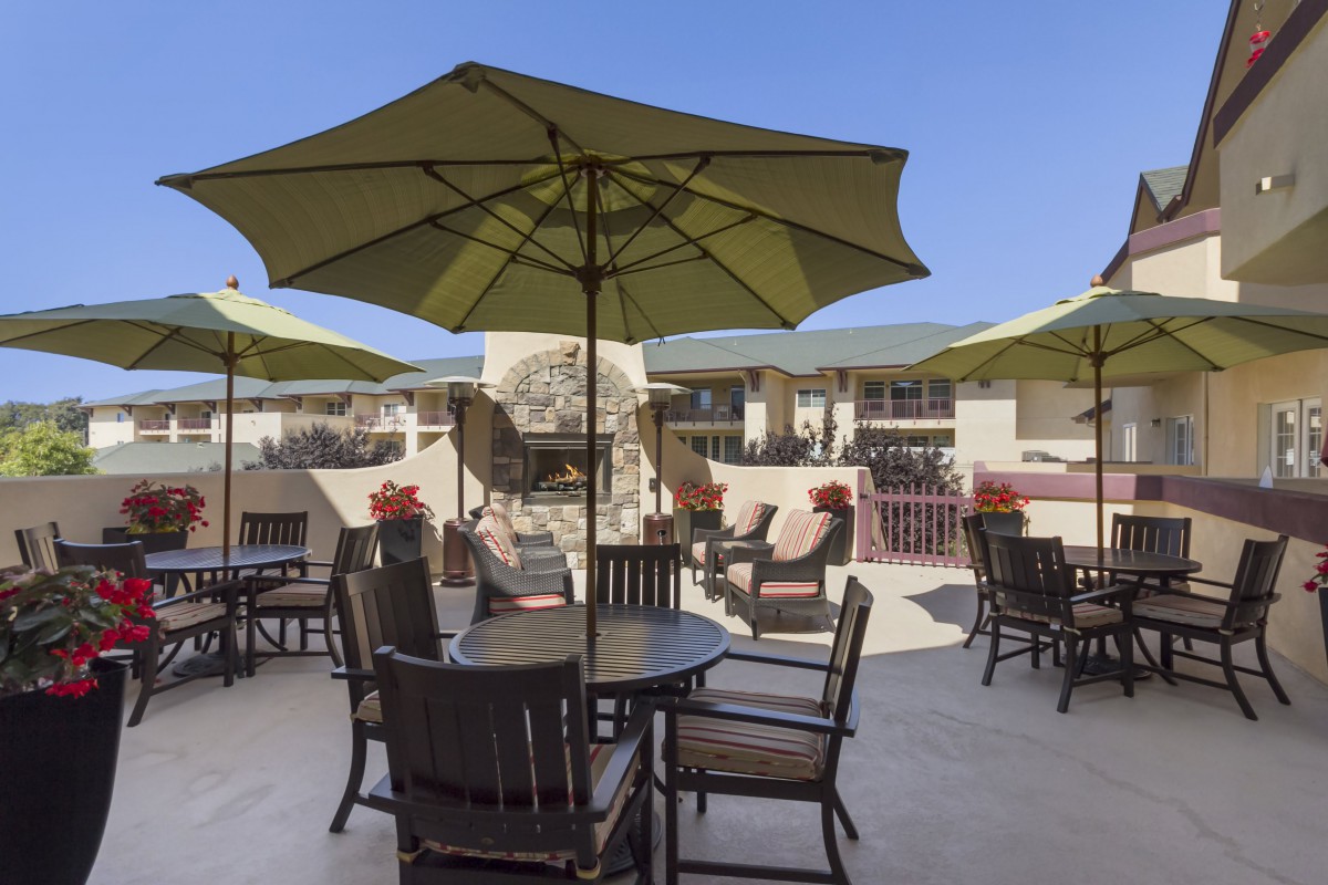 An inviting patio area with tables, chairs, and umbrellas under a clear blue sky.