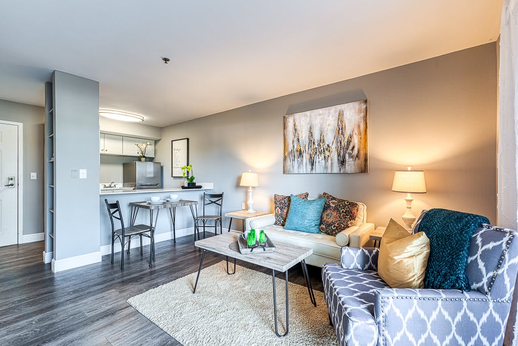 A modern living room with stylish decor, featuring a cozy sofa, elegant coffee table, and a connected kitchen area.