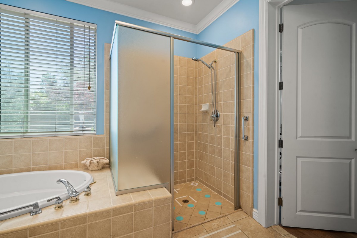 A modern bathroom featuring a glass-enclosed shower with tiled walls and natural light from a nearby window.
