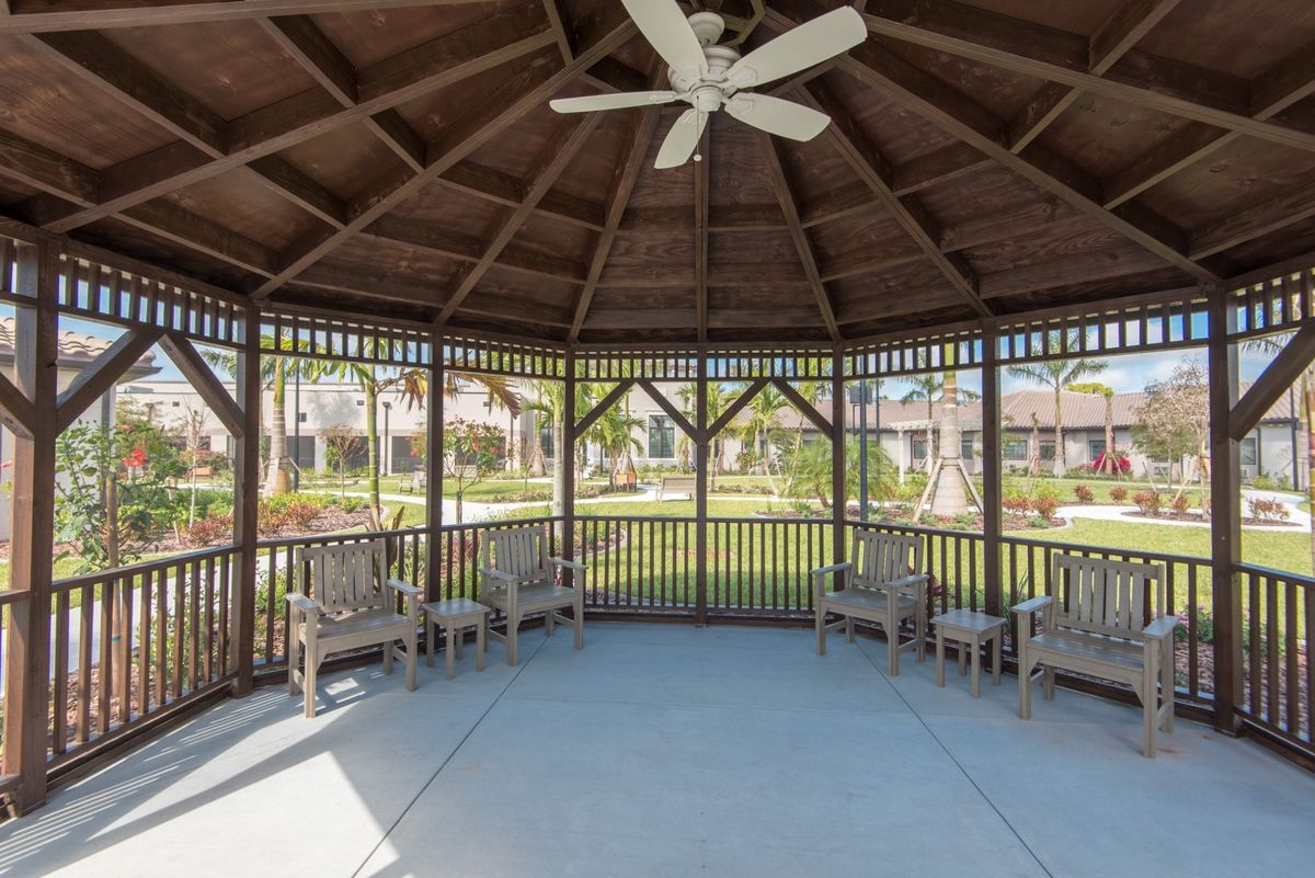 A spacious wooden gazebo with benches, located in a park setting.