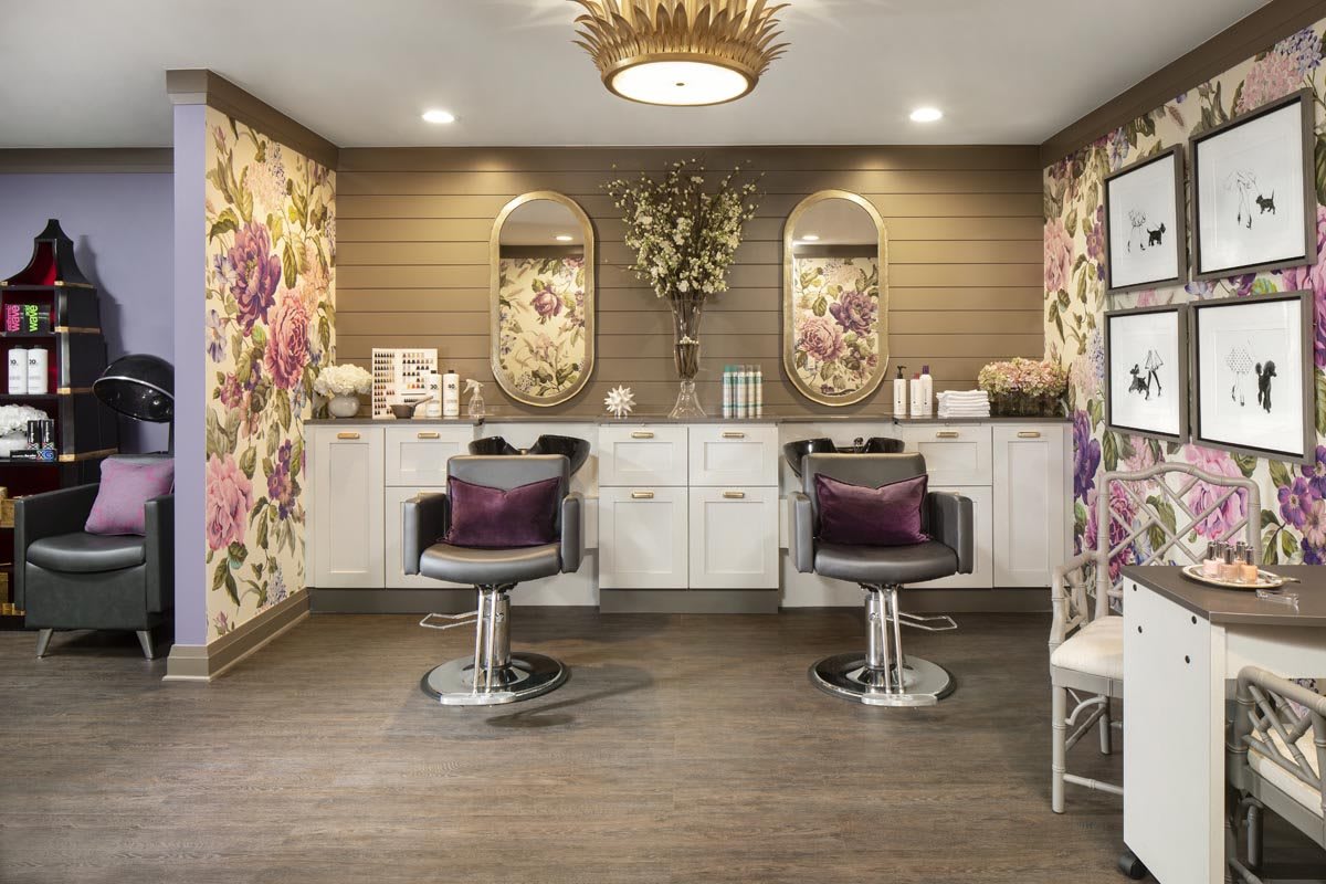 A luxurious hair salon interior with floral wallpaper, elegant chairs, and stylish mirrors.