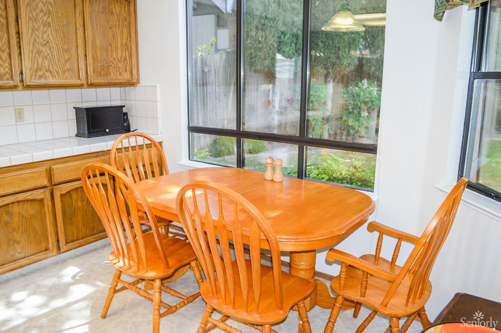 A cozy kitchen dining area with a wooden table and chairs next to a large window.