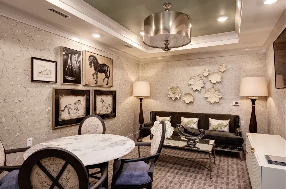 A stylishly decorated living room featuring elegant furniture, modern artwork, and a centerpiece chandelier.