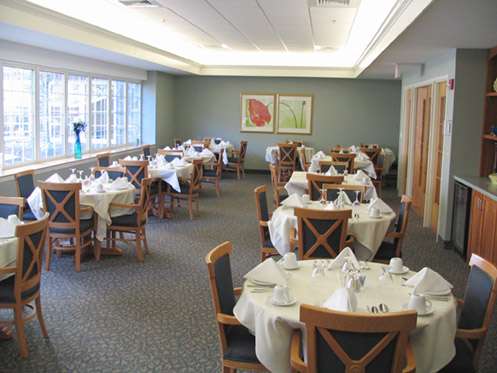 An elegantly set dining room with multiple tables and chairs, ready for guests.