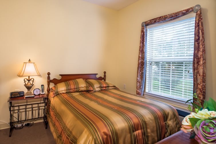 A cozy bedroom with a striped bedspread next to a window, featuring a bedside lamp.