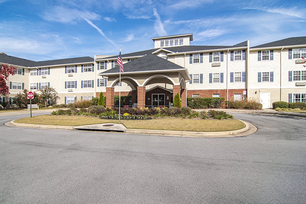 A modern residential building with an entrance featuring decorative landscaping and flags.