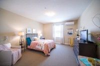 A cozy bedroom with a bed, bedside lamps, and a window providing natural light.