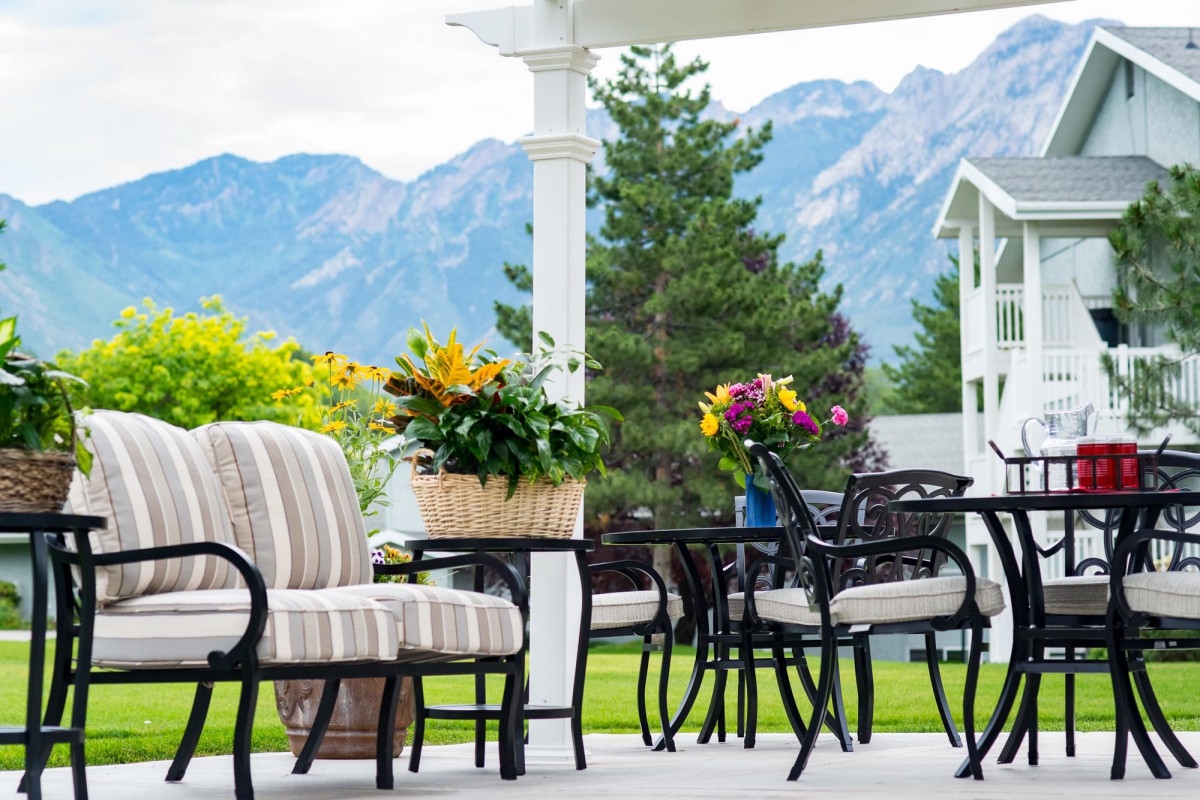 A cozy patio setup with comfortable seating, surrounded by lush greenery and a picturesque mountain backdrop.