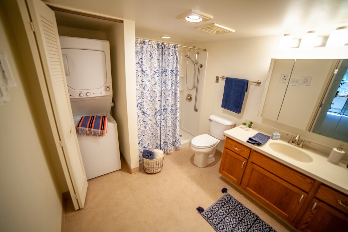 A well-organized bathroom with a washer and dryer, featuring blue and white accents.