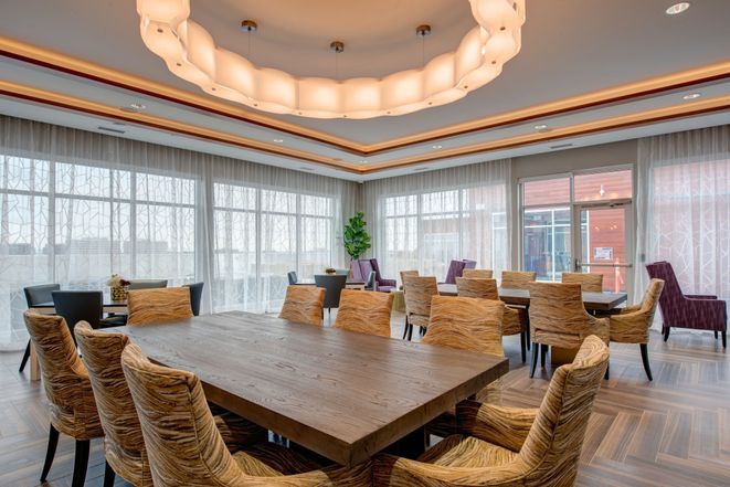 A modern conference room with a large wooden table, comfortable chairs, and ambient lighting.