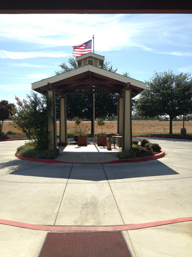 A charming outdoor pavilion with seating, surrounded by greenery and featuring the American flag.