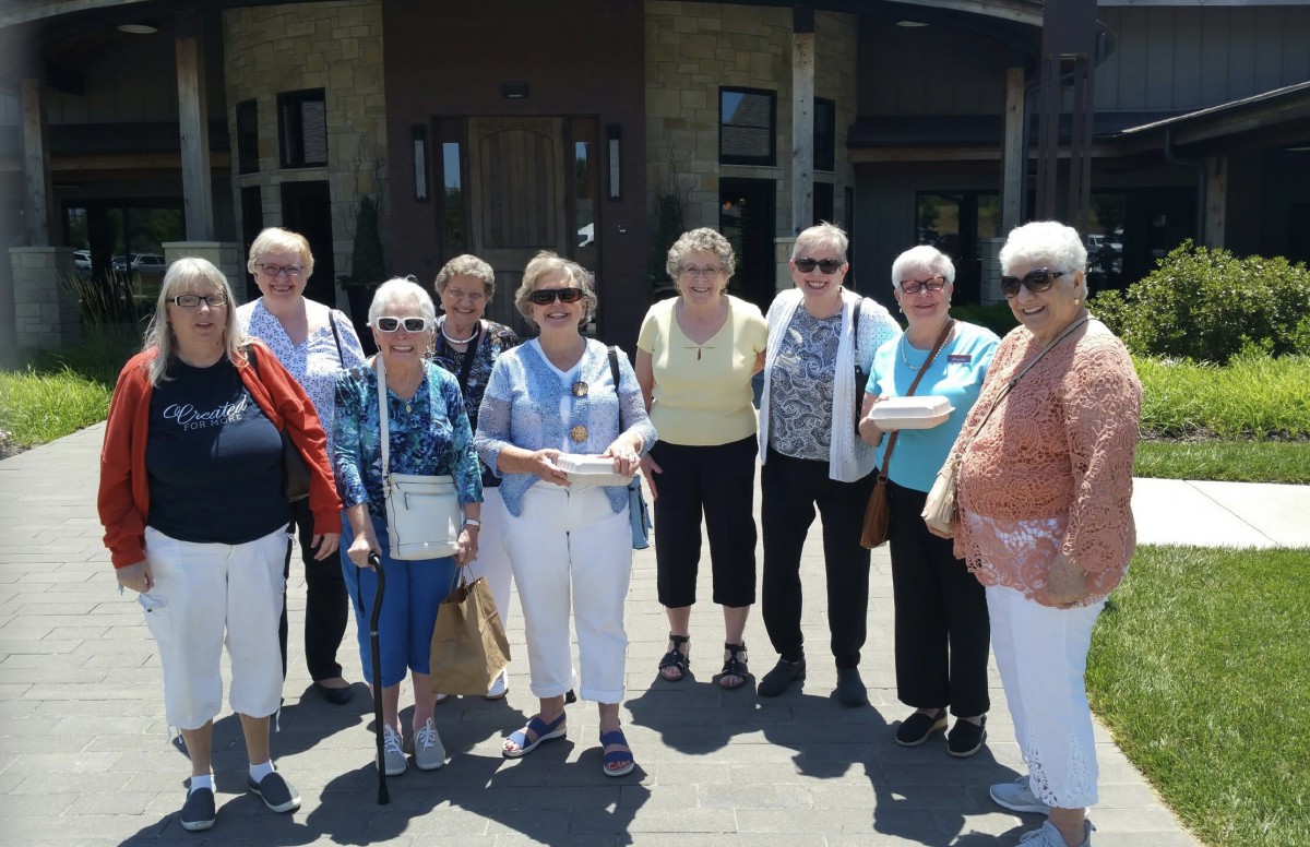 A group of senior individuals posing together outside on a sunny day.