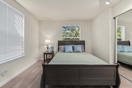 A cozy and modern bedroom featuring a bed, nightstand, and natural light from the window.