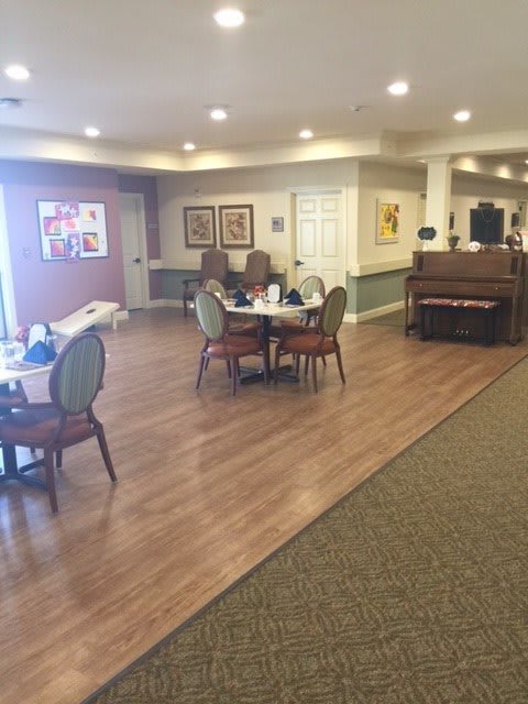 A well-lit dining area with tables, chairs, and a piano along with decorative artwork on the walls.